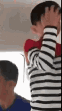 a man in a striped shirt is holding a child on his back .