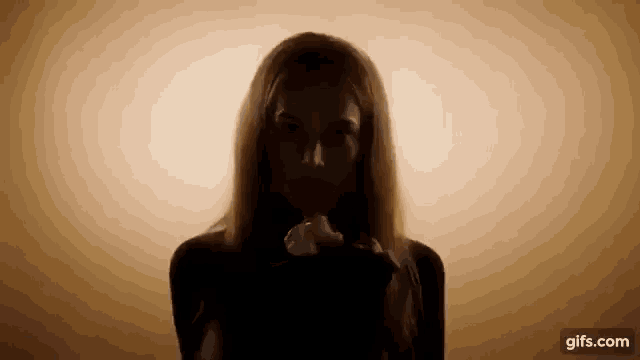 a woman is blowing a kiss in the dark while wearing a black dress .