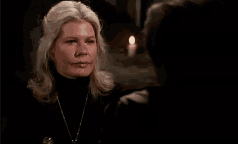 a woman in a black turtleneck is holding a cup of coffee in her hand .