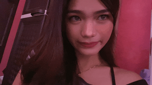 a woman in a black off the shoulder top is smiling for the camera
