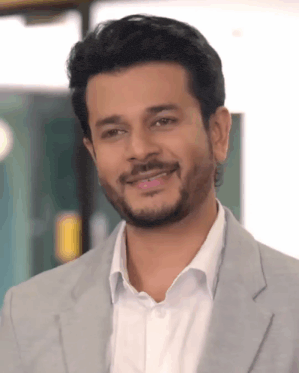a man with a beard wearing a suit and white shirt smiles for the camera
