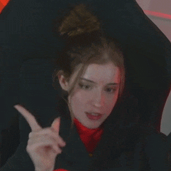 a woman in a black jacket and red shirt is giving a thumbs up