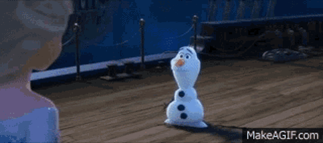 a snowman is standing on a wooden floor next to a woman .