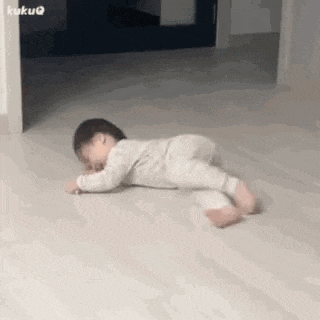 a baby is laying on its stomach on the floor in a room .