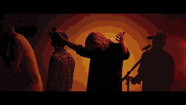 a group of people standing in front of a microphone with their hands in the air