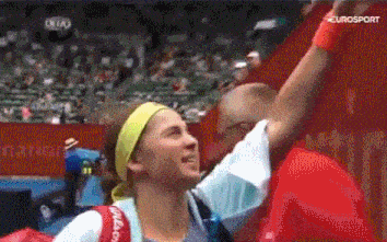 a woman in a yellow headband is being hugged by a man with eurosport written on the screen