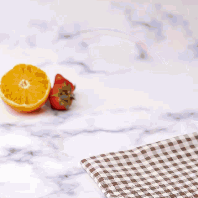 an orange and a strawberry next to a bowl on a plate