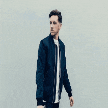a man in a blue jacket is standing in front of a wall that says sigala on it