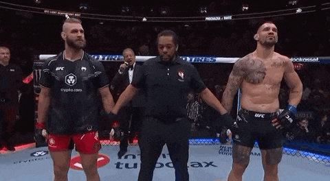 two men are standing next to each other on a boxing ring and holding hands .