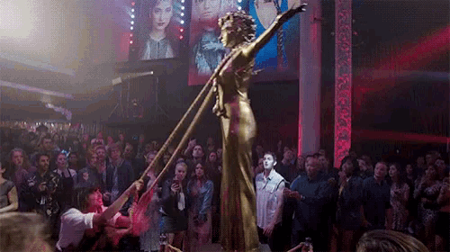 a statue of a woman holding a sword in front of a crowd of people