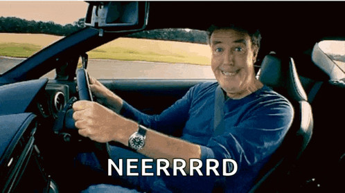 a man in a blue shirt is driving a car and the word neerrrrd is on the screen