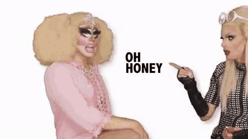 two drag queens are sitting next to each other and one of them is pointing at the other and saying `` oh honey '' .