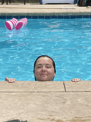 a woman in a swimming pool with a pink and white float floating in the water