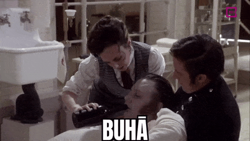 a man is drinking from a bottle while a woman looks on and the word buha is on the bottom right