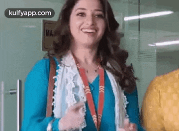 a woman wearing a lanyard and a blue shirt is smiling in an office .
