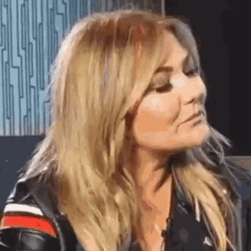 a close up of a woman wearing a leather jacket and making a funny face .
