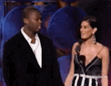 a man in a suit and a woman in a dress are standing next to each other .