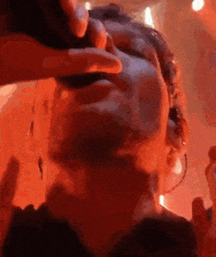 a close up of a person 's face in a dark room with a red background .