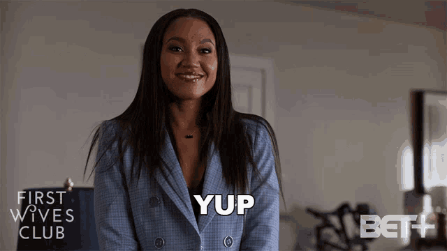 a woman in a suit is smiling and says yup