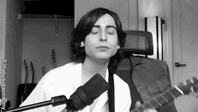 a man is singing into a microphone while playing a guitar .