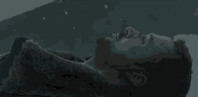 a man in a fur coat is laying down in the snow .