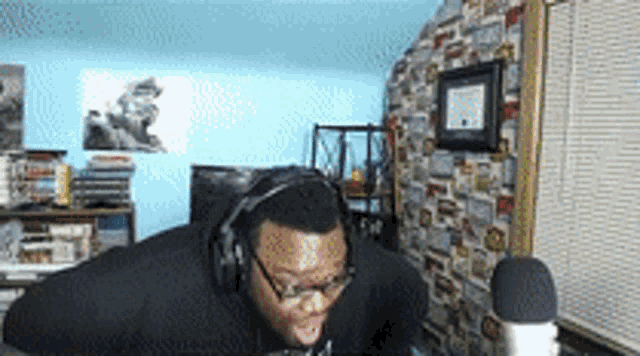 a man wearing headphones and glasses is talking into a microphone .