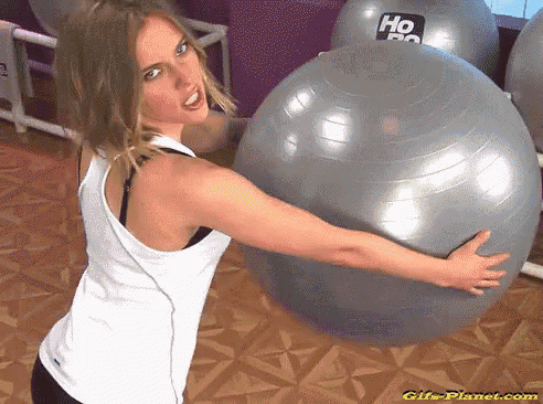 a woman in a white tank top holds a gray exercise ball with the word ho on it