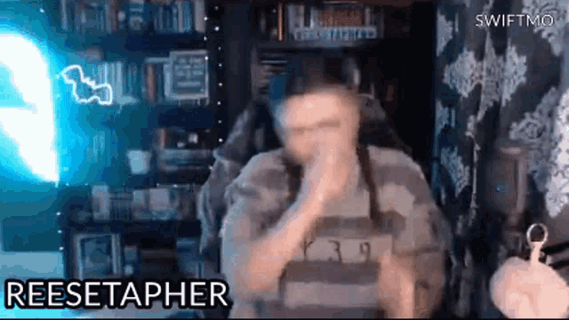 a man is sitting in a chair in front of a microphone and covering his mouth with his hand .