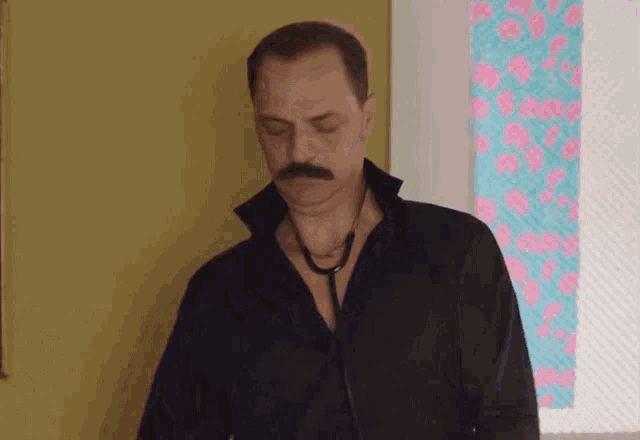 a man with a mustache is wearing a black shirt and a stethoscope around his neck