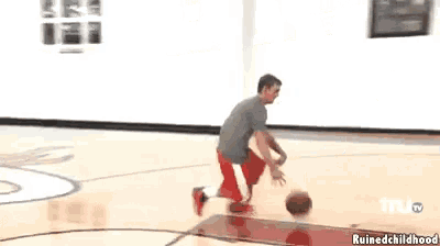 two boys are playing basketball in a room with pictures on the wall