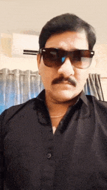 a man wearing sunglasses and a black shirt has a mustache