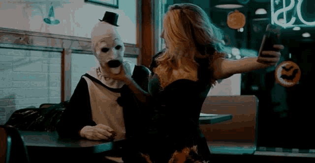 a woman takes a selfie with a clown in a top hat