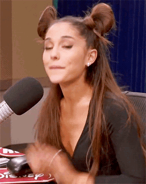 a woman with two buns on her hair is sitting in front of a microphone