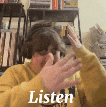 a person wearing headphones covering their face with their hands in front of a sign that says listen on it