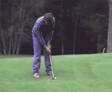 a man in a plaid shirt is hitting a golf ball