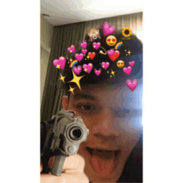 a young man is holding a gun in front of his face with hearts on it