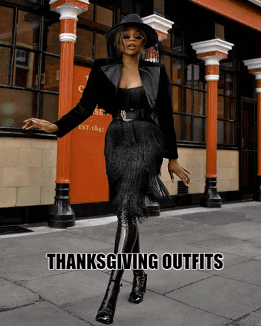 a woman in a black dress is standing in front of a building that says thanksgiving outfits on it