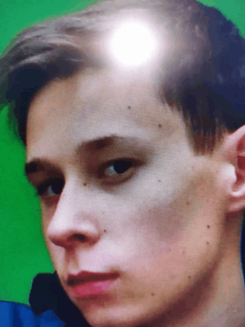 a close up of a young man 's face with a white light shining on his forehead