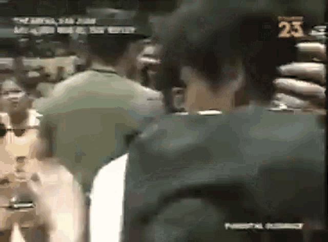 a man is taking a picture of a group of people in a crowd on a television screen .