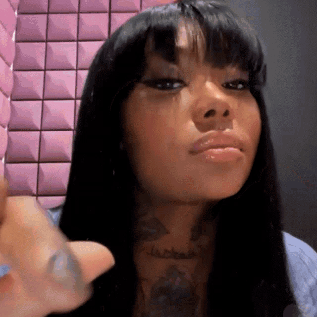 a woman with long hair and a tattoo on her neck is giving a thumbs up