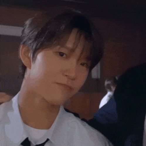 a young man wearing a white shirt and tie looks at the camera .