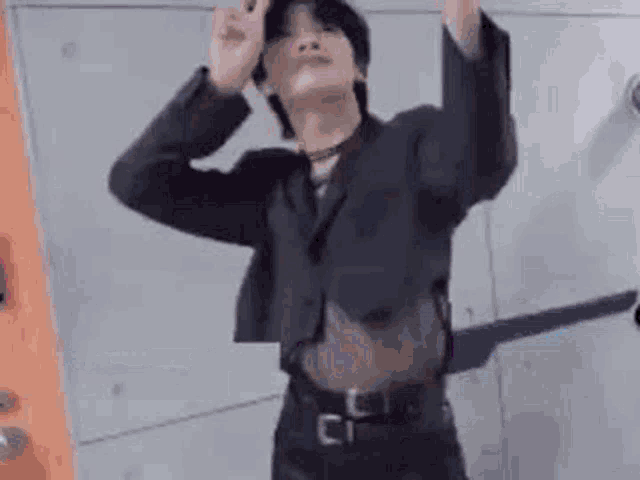 a man in a suit is dancing in front of a wall .