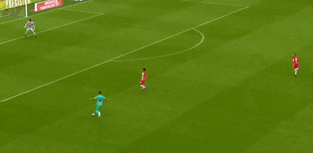 a soccer game is being played on a field with a red bull advertisement behind the goal