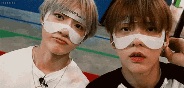 two young men wearing masks are standing next to each other .