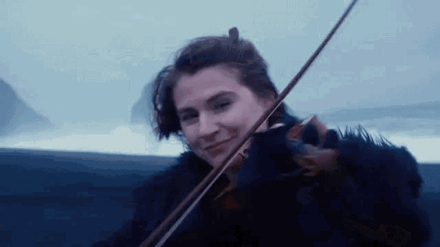 a woman in a fur coat is playing a violin in the rain .