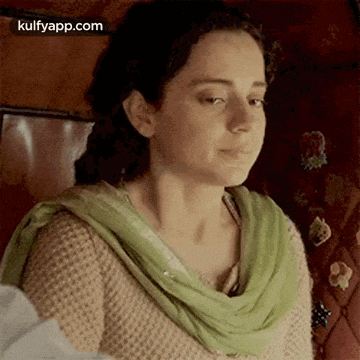 a close up of a woman wearing a green scarf and a beige sweater .