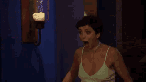 a woman in a white dress is making a surprised face while standing in front of a stained glass window .