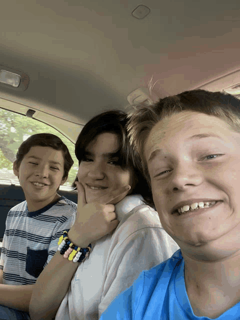 three boys in a car with one wearing a bracelet
