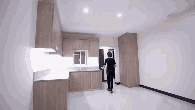 a person standing in a kitchen with wooden cabinets and white counter tops