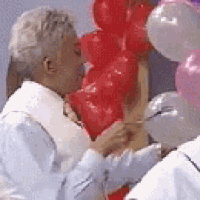 a man is holding a bunch of balloons in his hands .
